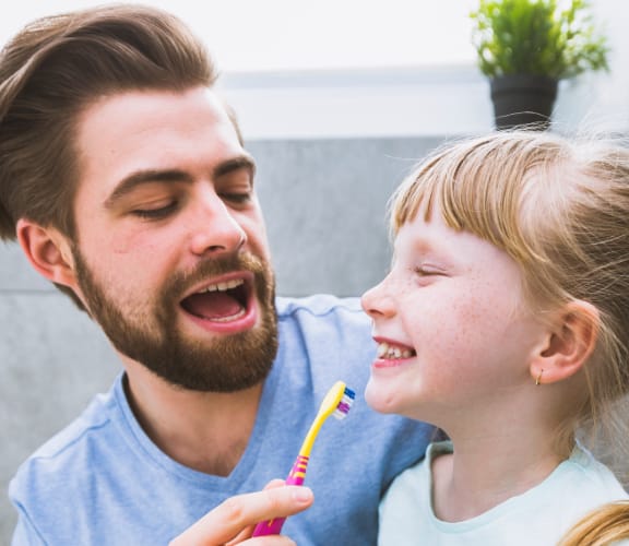 Father brushing his daughters teeth