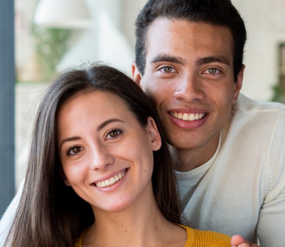 Couple sitting on couch holding each other and smiling
